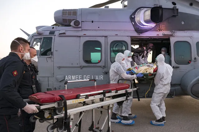 In this photo provided by the French Army Thursday, April 2, 2020, medical staffs evacuate a patient infected with the Covid-19 virus, Wednesday April 1, 2020 at Orly airport, south of Paris. The operation aims at relieving hospitals in the Paris region, hardly hit by the coronavirus. (Photo by Julien Fechter/DICOD via AP Photo)