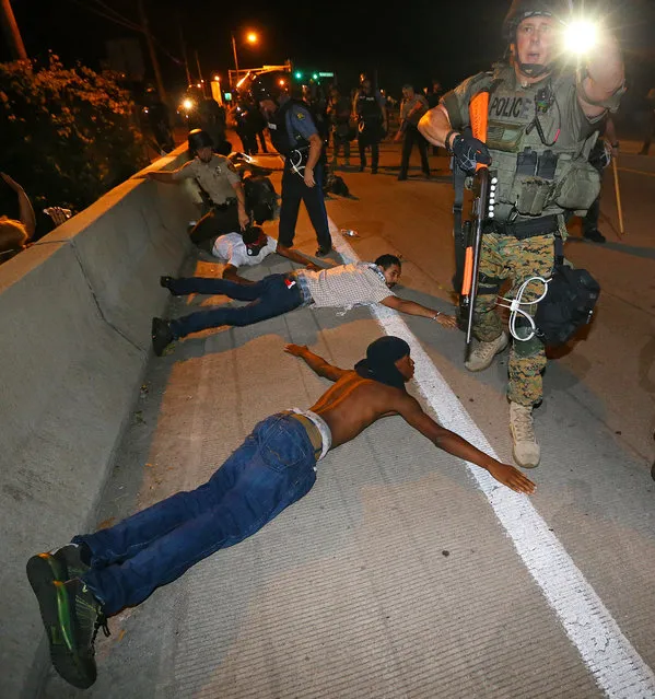 Police begin arresting dozens of protesters on West Florissant Avenue after they refused to leave the area and some began throwing objects at officers in Ferguson, Mo. early Wednesday, August 20, 2014. On Aug. 9, 2014, a white police officer fatally shot Michael Brown, an unarmed black 18-year old, in the St. Louis suburb. (Photo by Curtis Compton/AP Photo/Atlanta Journal-Constitution)