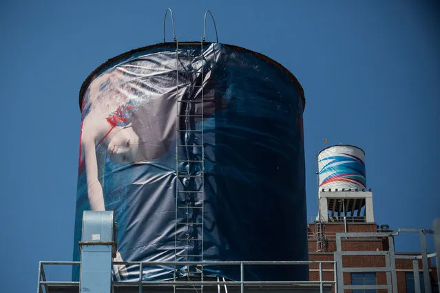 Two water tanks, reimagined and wrapped as artistic canvases by artists Laurie Simmons (L) and Odili Donald Odita (R) for The Water Tank Project, are seen on August 27, 2014 in the Chelsea neighorhood of New York City. The Water Tank Project will wrap over 100 water tanks around New York City with art by both new and established artists through the end of  October 2014. The goal of the project is to raise awareness about water usage and the environment. (Photo by Andrew Burton/Getty Images)