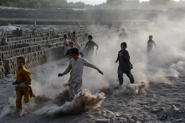 In this photograph taken on August 16, 2017, Afghan children run as they play along a dusty road on the outskirts of Jalalabad. (Photo by Noorullah Shirzada/AFP Photo)