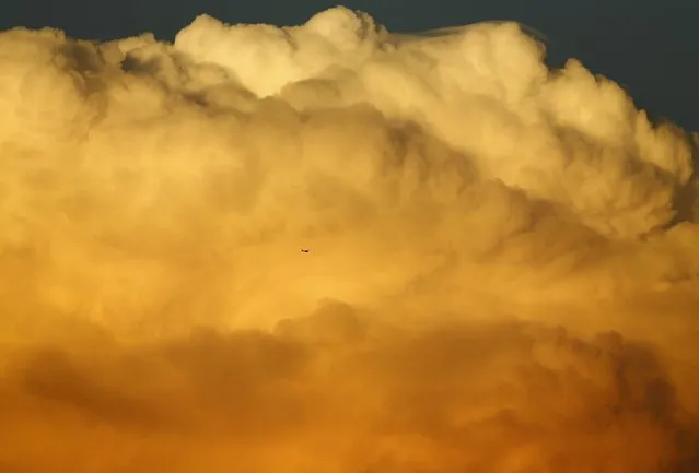 A small aircraft flies past a large emerging thunderstorm during sunset near Encinitas, California September 8, 2014. (Photo by Mike Blake/Reuters)
