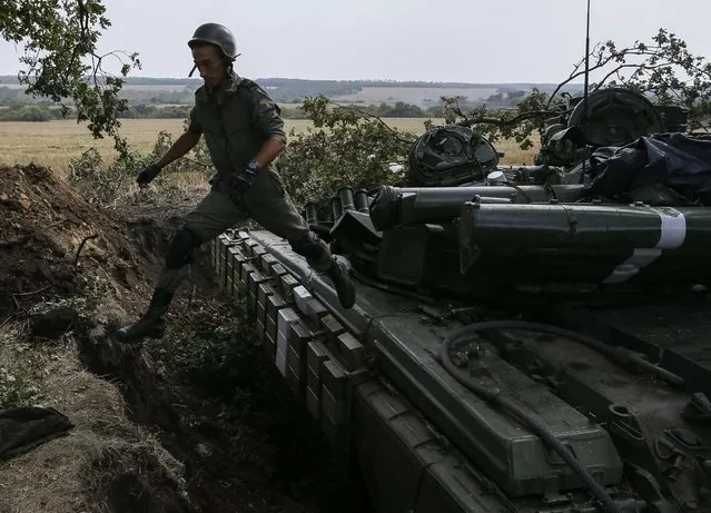 A Ukrainian soldier jumps from a tank near the eastern Ukrainian town of Pervomaysk September 12, 2014. Ukraine's president said on Friday there could be no military solution to his country's crisis and said he hoped “a very fragile” ceasefire in the east would hold, allowing him to focus on rebuilding the shattered economy. (Photo by Gleb Garanich/Reuters)