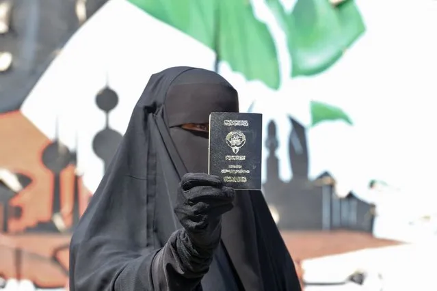A Kuwaiti woman displays her passport as she votes during parliamentary elections in Kuwait City on September 29, 2022. Kuwait will holds its most inclusive elections in a decade today with some opposition groups ending a boycott after the oil-rich country's royal rulers pledged not to interfere with parliament. (Photo by Yasser Al-Zayyat/AFP Photo)