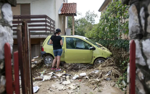 A woman stands by a damaged car in the house yard after flooding, in the village of Stajkovci, just east of Skopje, Macedonia, on Monday, August 8, 2016. Macedonia's government declared a state of emergency Sunday in parts of the capital hit by torrential rain and floods that left at least 21 people dead, six missing and dozens injured, authorities said. (Photo by Boris Grdanoski/AP Photo)