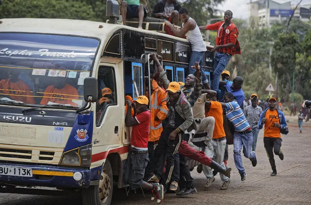 Supporters of opposition leader Raila Odinga ride on the outside of a “matatu” minibus as they arrive for a rally in Uhuru Park in downtown Nairobi, Kenya Wednesday, October 25, 2017. (Photo by Ben Curtis/AP Photo)