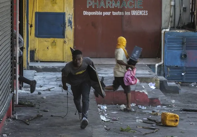A man runs away with looted goods during a protest against fuel price hikes and to demand that Haitian Prime Minister Ariel Henry step down, in Port-au-Prince, Haiti, Thursday, September 15, 2022. (Photo by Joseph Odelyn/AP Photo)