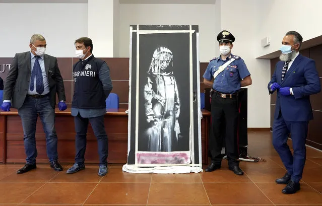 Italian authorities unveil a stolen artwork painted by the British artist Banksy as a tribute to the victims of the 2015 terror attacks at the Bataclan music hall in Paris,  during a press conference in L' Aquila, Italy, Thursday June, 11, 2020 . The L' Aquila prosecutors office said the work was recovered on Wednesday during a search of a home in Tortoreto, a city near the Adriatic coast in the Abruzzo region's Teramo province. (Photo by Andrea Rosa/AP Photo)