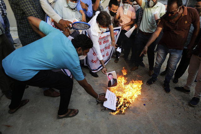 An Indian man burns a photograph of Chinese president Xi Jinping during a protest against China in Ahmedabad, India, Tuesday, June 16, 2020. At least three Indian soldiers, including a senior army officer, were killed in a confrontation with Chinese troops along their disputed border high in the Himalayas where thousands of soldiers on both sides have been facing off for over a month, the Indian army said Tuesday. (Photo by Ajit Solanki/AP Photo)