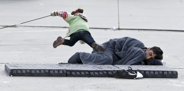 A migrant child stumbles over a man who sleeps on the street at the Austria-Hungaria border in Nickelsdorf, Austria, September 20, 2015. (Photo by David W. Cerny/Reuters)