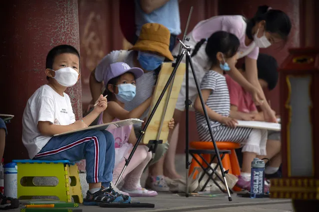 Children wearing face masks to protect against the coronavirus sketch the Temple of Heaven in Beijing, Saturday, July 18, 2020. (Photo by Mark Schiefelbein/AP Photo)