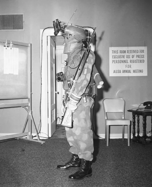 A soldier in Washington on August 3, 1959, models a uniform and equipment for the army of the future. Mask, gloves and other parts of the uniform are designed to give protection against nuclear explosions. The helmet contains a radio receiver. Hooked to the helmet are infra-red binoculars for protection against enemy infra-red detecting devices, an image meta-scope, hang from chain around the neck. On his back the soldier has an explosive fox-hole digger. The rifle is an M-14, which fires a 7.62 millimeter bullet. (Photo by John Rous/AP Photo)