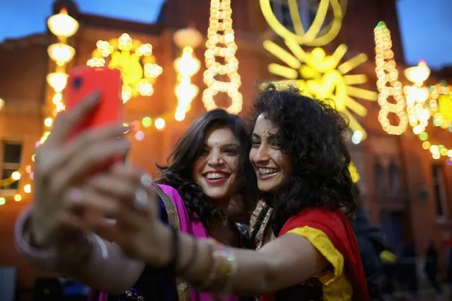 Friends Aanka Batta (L) and Kelly Vaduka take a selfi in front of illuminations as they celebrate the Hindu festival of Diwali on October 23, 2014 in Leicester, England. Up to 35,000 people attended the Bandi Chhor Divas, commonly known as the Diwali festival of light, in Leicester's Golden Mile in the heart of the city's Asian community. The festival is an opportunity for Hindus to honour Lakshmi, the goddess of wealth and other gods. Leicester's celebrations are one of the biggest in the world outside India. (Photo by Christopher Furlong/Getty Images)