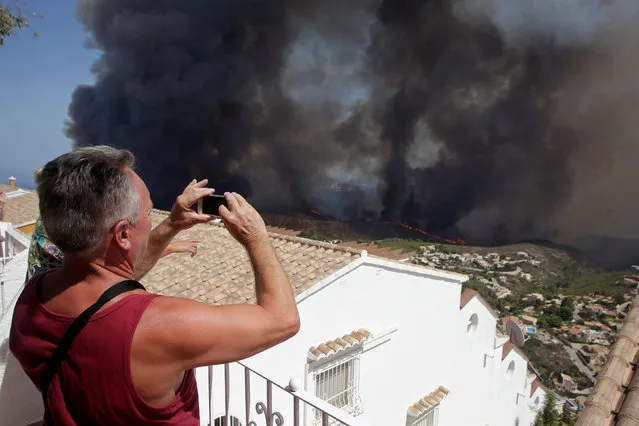 A tourist takes pictures of a wildfire in Benitatxell near Alicante, Spain September 5, 2016. (Photo by Heino Kalis/Reuters)