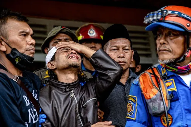 Ahmad Ashikin (2L), father of seven-year-old Indonesian girl Ashika Nur Fauziah, reacts after rescue personnels found her dead under the rubble at Cugenang village, in Cianjur, on November 25, 2022. Ashika Nur Fauziah, also known as Cika, was the subject of a day-long rescue effort after an earthquake killed 272 people in West Java. Emergency workers found her body under rubble in the worst-hit district of Cianjur. (Photo by Mas Agung Wilis/AFP Photo)