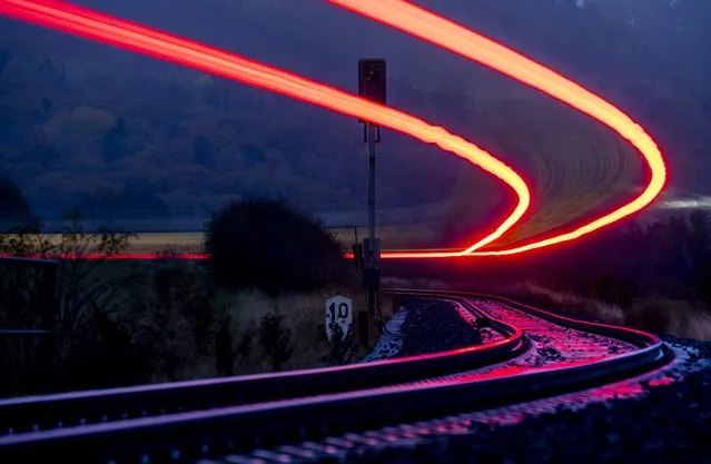Long time exposure photo shows a regional train approaching the train station of Wehrheim near Frankfurt, Germany, early Thursday, November 24, 2022. (Photo by Michael Probst/AP Photo)