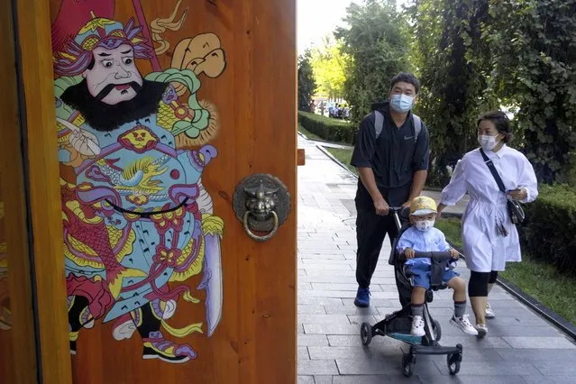 Residents wearing masks to curb the spread of the coronavirus walk on a Beijing street on Monday, August 24, China has gone several days without reporting a new local case of COVID-19, with the Beijing International Film Festival among public events that are returning. (Photo by Ng Han Guan/AP Photo)