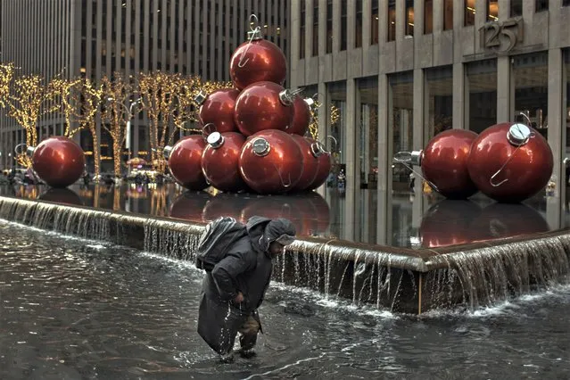 A man collects coins walking inside a cold fountain on Christmas Day, Sunday, December 25, 2022, in New York. (Photo by Andres Kudacki/AP Photo)