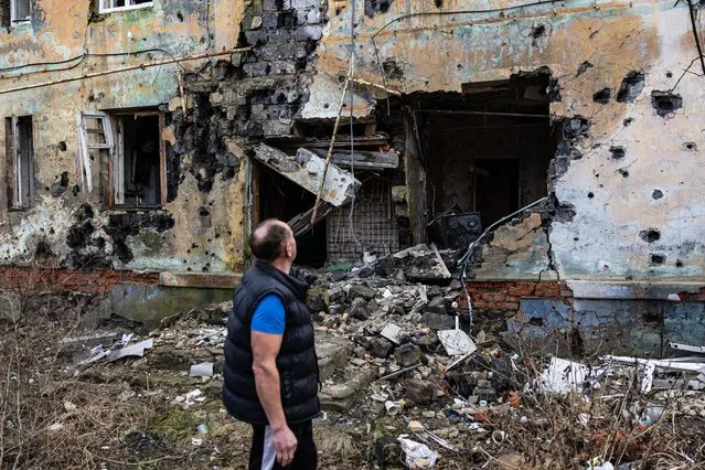 60-year-old, Andryi Pleshan, checks destruction around his shelter in the city of Izium, eastern Ukraine on January 2, 2023. During the long months of Russian occupation in Izium, Andryi Pleshan took in up to 60 people in his basement. Among them was Nyka, a two-month-old baby, whose presence permeates the shelter where the 60-year-old still lives. (Photo by Sameer Al-Doumy/AFP Photo)