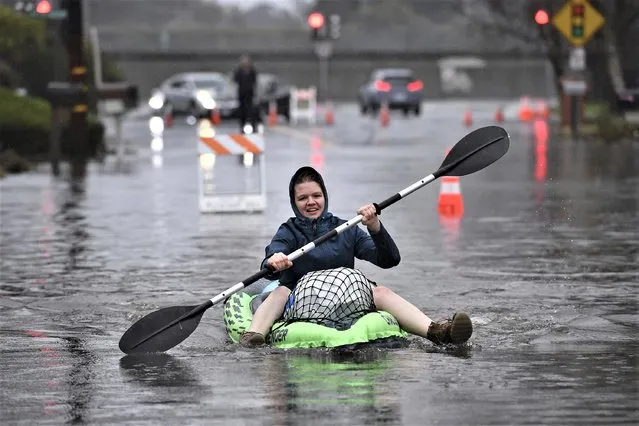 Nurse Katie Leonard uses a kayak to bring supplies to Patsy Costello, 88, as she sits trapped in her vehicle for over an hour on Astrid Drive in Pleasant Hill, Calif., on Saturday, December 31, 2022. Costello drove her car on the flooded street thinking she could make it when it stalled in the two feet of water. After two hours the water had receded about a foot making it easier to rescue her. Police were called but stood by and watched after calling in a tow truck to help pull the car out of the water. Nurse Katie Leonard, of Pleasant Hill, lives down the block used her kayak to bring Costello hot tea, blankets, food and a phone to call a friend. (Photo by Jose Carlos Fajardo/Bay Area News Group via AP Photo)