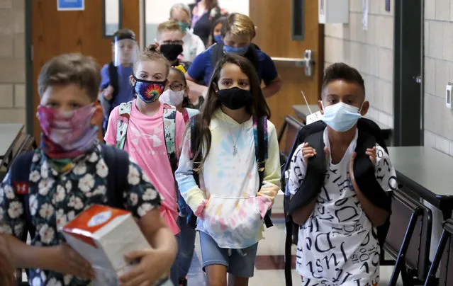 Wearing masks to prevent the spread of COVID19, elementary school students walk to classes to begin their school day in Godley, Texas, Wednesday, August 5, 2020. Three rural school districts in Johnson County were among the first in Texas to head back to school for in person classes for students. (Photo by L.M. Otero/AP Photo)