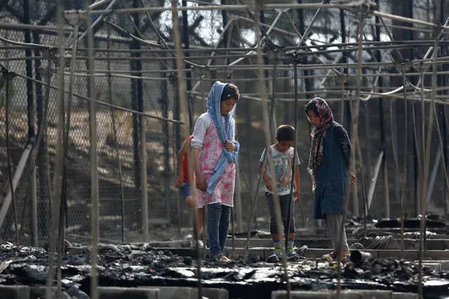 Migrants stand among the remains of a burned tent at the Moria migrant camp, after a fire that ripped through tents and destroyed containers during violence among residents, on the island of Lesbos, Greece, September 20, 2016. (Photo by Giorgos Moutafis/Reuters)