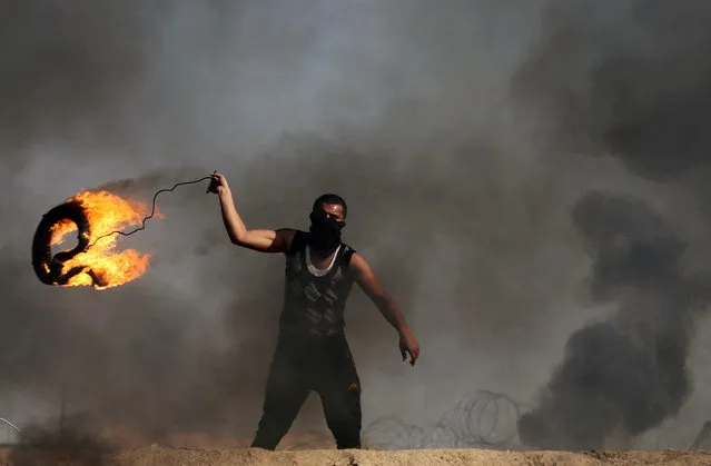 A Palestinian demonstrator prepares to hurl a burning tire at Israeli troops during clashes near the border with Israel in the southern Gaza Strip February 2, 2018. (Photo by Ibraheem Abu Mustafa/Reuters)