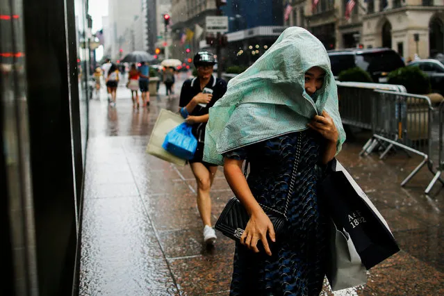 People walk during a pouring rain in Manhattan, New York, U.S., August 20, 2016. (Photo by Eduardo Munoz/Reuters)