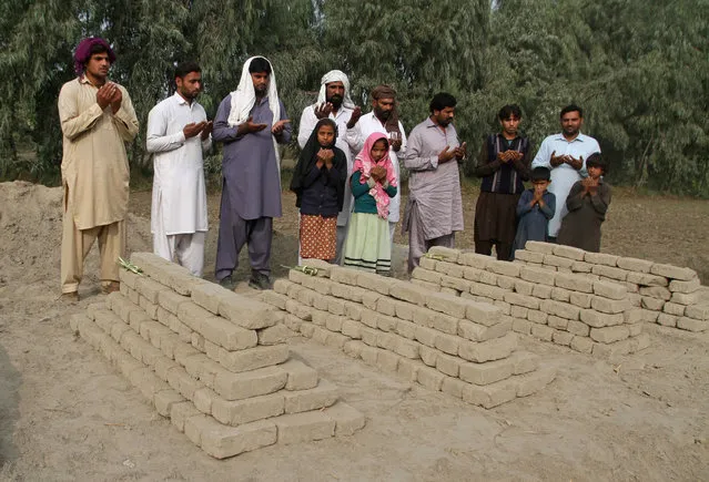 Relatives of poisoning victims pray at their graves in Basti Lashari, Pakistan, Wednesday, November 8, 2017. Pakistani police arrested a woman for allegedly plotting with her newly married niece to poison the niece's husband with tainted milk that also ended up killing 17 other in-laws in a remote village. (Photo by Iram Asim/AP Photo)