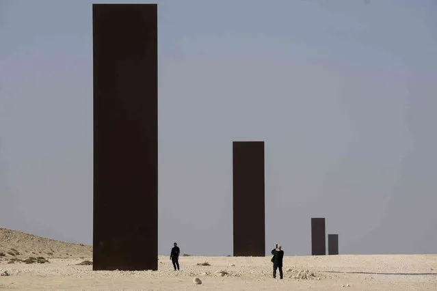 People view American artist Richard Serra's “East-West/West-East” art as it stands in a desolate section of the Brouq Nature Reserve in the northwestern part of the country's desert close to Zekreet, Qatar, Saturday, December 3, 2022. Four steel plates, each 14 meters high, span a one-kilometer stretch of the desert. (Photo by Nathan Denette/The Canadian Press via AP Photo)