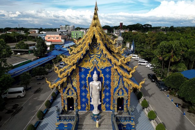 This aerial photograph shows a tourist posing for photos at the Wat Rong Suea Ten Buddhist temple, popularly known as “Blue Temple”, in northern Thailand's Chiang Rai province on May 26, 2025. (Photo by Manan Vatsyayana/AFP Photo)