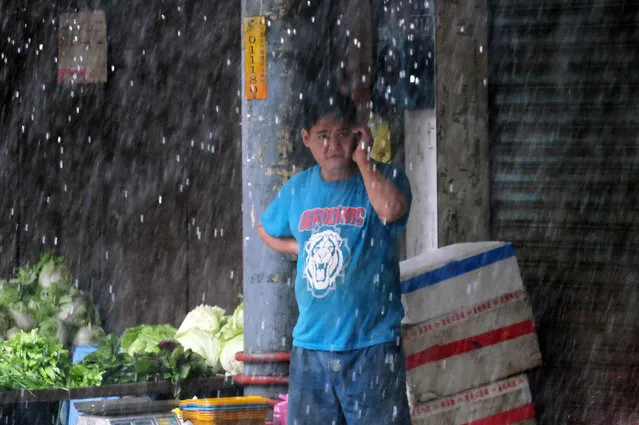 A vegetable vendor speaks on the cellphone at a market in Xindian district of the New Taipei City, as Typhoon Megi approaching the east Taiwan on September 27, 2016. (Photo by Sam Yeh/AFP Photo)
