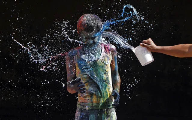 A boy smeared with colours reacts as another boy pours water on him during Holi celebrations in the southern Indian city of Chennai March 27, 2013. Holi, also known as the Festival of Colours, heralds the beginning of spring and is celebrated all over India. (Photo by Babu/Reuters)