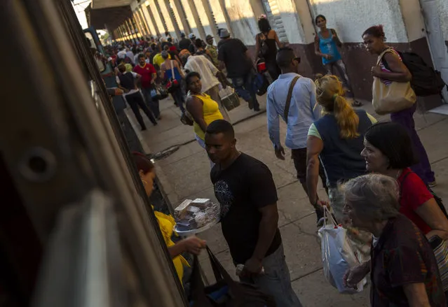 In this March 23, 2015 photo, a street vendor sells homemade sweets to travelers at a train station in the Ciego de Avila province in Cuba. At their peak, Cuban trains featured dining cars and other high-end services. Today, refreshment comes from the vendors who board at many stations offering cold sandwiches and soft drinks. (Photo by Ramon Espinosa/AP Photo)
