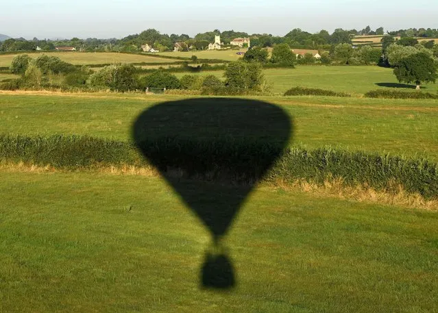 The shadow of a balloon is seen over fields during a mass launch at the annual Bristol International Balloon Fiesta, near Bristol, Britain on August 12, 2022. (Photo by Toby Melville/Reuters)
