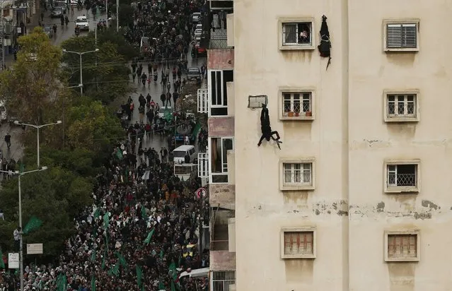 Palestinian members of al-Qassam Brigades, the armed wing of the Hamas movement, rappel from a building upside down during a military parade marking the 27th anniversary of Hamas' founding, in Gaza City December 14, 2014. (Photo by Suhaib Salem/Reuters)