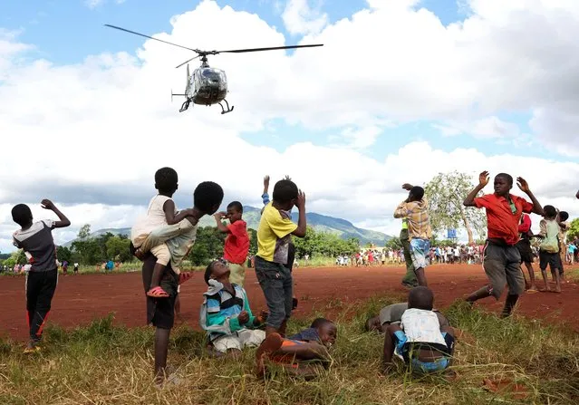 Children in Mulanje looks on as a military helicopter carry doctors and medical supplies to Muloza on the border with Mozambique which are cut off after the tropical Cyclone Freddy outside Blantyre, Malawi on March 18, 2023. (Photo by Esa Alexander/Reuters)