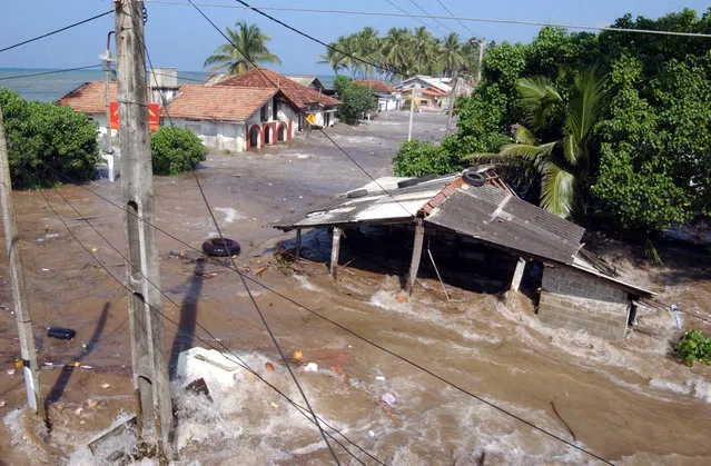 In this December 26, 2004 file photo, tidal waves wash through houses at Maddampegama, about 60 kilometers (38 miles) south of Colombo, Sri Lanka. (Photo by Gemunu Amarasinghe/AP Photo)