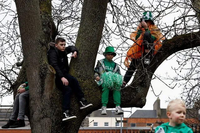 Children sit on tree branches during the St. Patrick's Day parade in Dublin, Ireland on March 17, 2023. (Photo by Clodagh Kilcoyne/Reuters)