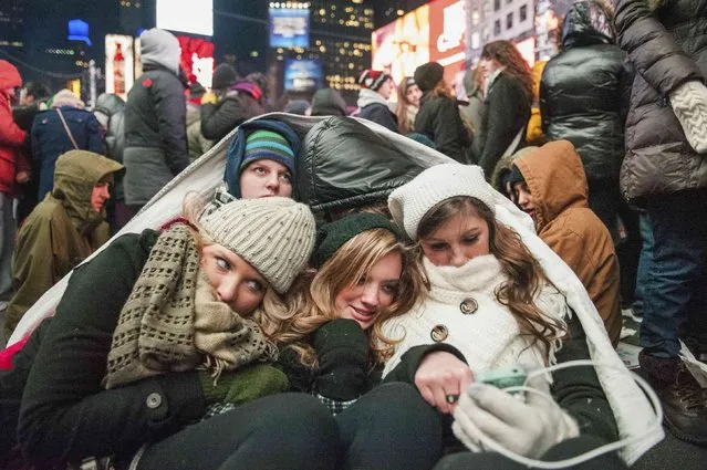 Friends from the U.S. state of Kentucky huddle while taking refuge from the cold weather during New Year's Eve celebrations in Times Square, New York December 31, 2014. (Photo by Stephanie Keith/Reuters)
