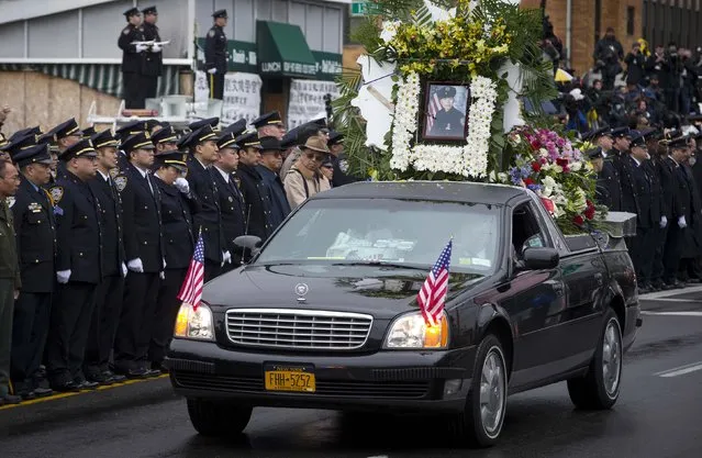 A flower car leads the hearse carrying the casket of New York Police Department officer Wenjian Liu in a procession down 65th Street following his funeral service in the Brooklyn borough of New York January 4, 2015. (Photo by Mike Segar/Reuters)