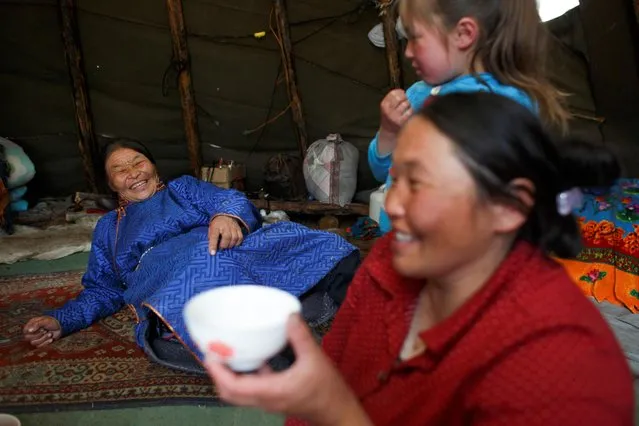 Ethnic Dukha Jargal Gombosed talks with her daughter and granddaughter in their tent in a forest near the village of Tsagaannuur, Khovsgol aimag, Mongolia, April 20, 2018. “In my day, everything, like rice and flour, were really rare. But now, as long as you have money, you can get anything, any clothes”, Gombosed said. “Things were different in the past”, she said. “When I was young we didn't have any such thing as a phone, so you would only hear news when you went down to the village centre. But now people have phones and also TVs”. (Photo by Thomas Peter/Reuters)