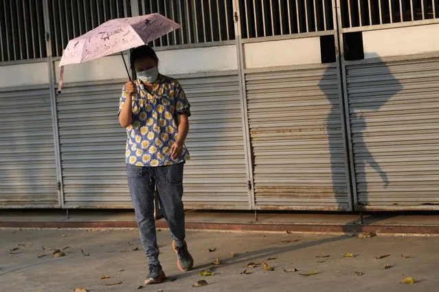 A woman holds an umbrella to shelter from the sun in Bangkok, Thailand, Saturday, April 22, 2023. The authorities warned residents across Thailand to avoid outdoor activities due to extreme heat over the weekend. (Photo by Sakchai Lalit/AP Photo)
