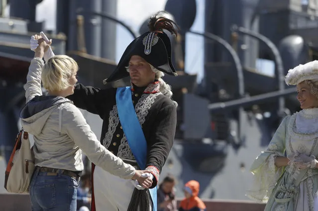 Actors in period costume pose with tourists in front of the cruiser Aurora, a museum ship at the 2018 soccer World Cup, in St Petersburg, Russia, Wednesday, June 20, 2018. (Photo by Alastair Grant/AP Photo)