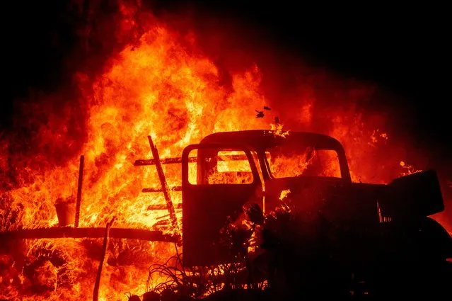 Flames consume a vintage truck as the Bond Fire burns through the Silverado community in Orange County, Calif., on Thursday, December 3, 2020. (Photo by Noah Berger/AP Photo)