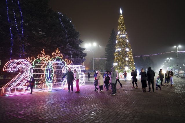 People walk in a square decorated for Christmas and the New Year festivities in Donetsk in Russian-controlled Donetsk region, eastern Ukraine, Tuesday, December 31, 2024. (Photo by Alexei Alexandrov/AP Photo)
