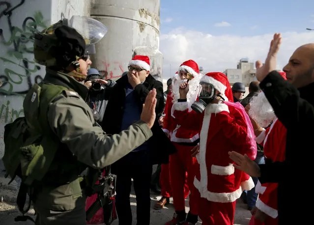 Palestinian protesters wearing Santa Claus costumes argue with an Israeli border policeman during an anti-Israel protest near the Israeli barrier in the West Bank city of Bethlehem December 18, 2015. (Photo by Ammar Awad/Reuters)