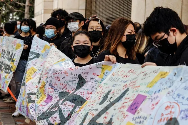 Supporters of pro-democracy activists hold a banner as they queue up for a court hearing over national security law outside West Kowloon Magistrates' Courts, in Hong Kong, China on March 1, 2021. (Photo by Tyrone Siu/Reuters)