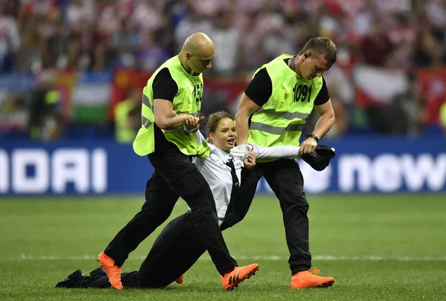 Stewards pull a woman off the pitch after she stormed onto the field and interrupted the final match between France and Croatia at the 2018 soccer World Cup in the Luzhniki Stadium in Moscow, Russia, Sunday, July 15, 2018. (Photo by Martin Meissner/AP Photo)