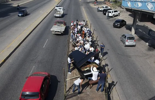 Musicians join pianist, composer and conductor Jose Agustin Sanchez on the bed of an 18-wheeler truck for a musical tour coined a “musical disinfection” in Barquisimeto, Venezuela, Thursday, March 4, 2021. (Photo by Ariana Cubillos/AP Photo)