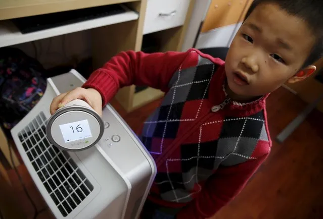 Jiang Zhen's son Doudou shows the air quality around an air purifier with a portable device that measures air quality during an interview with Reuters in his house, on the second day after China's capital Beijing issued its second ever “red alert” for air pollution, in Beijing, China, December 20, 2015. (Photo by Kim Kyung-Hoon/Reuters)